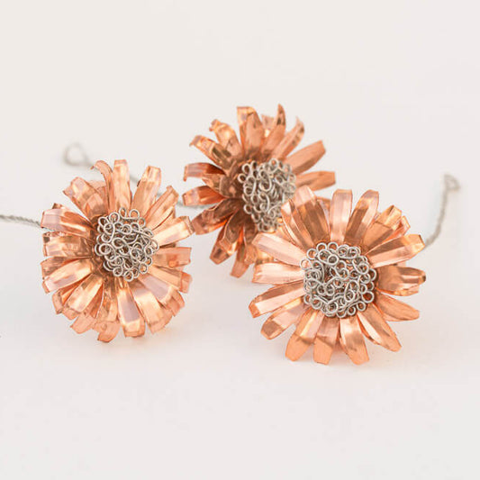 Copper and stainless steel daisies on white background