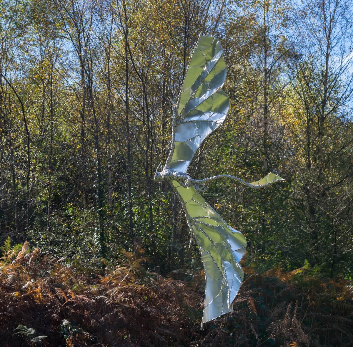 Dragon sculpture reflecting colours against trees