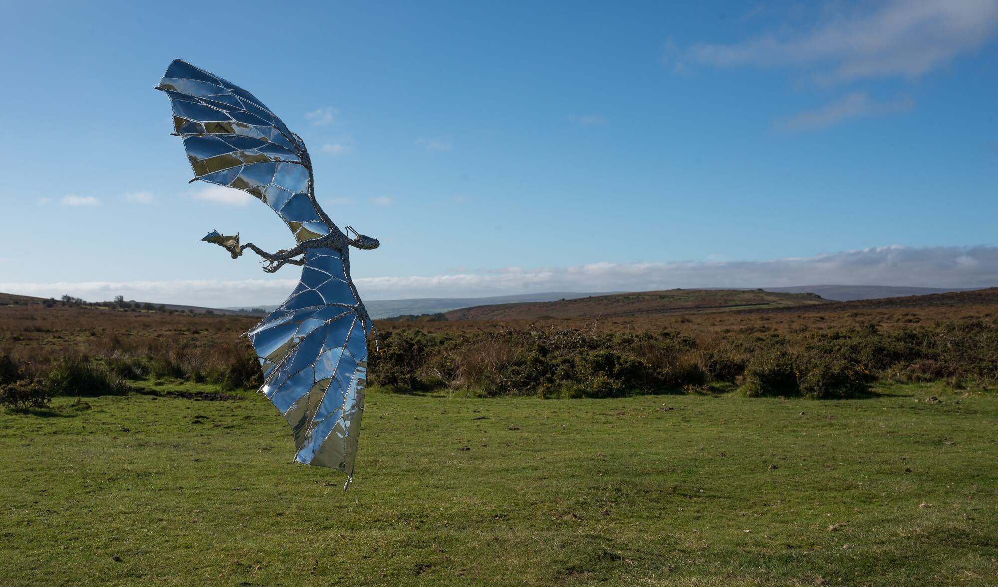 Stainless steel dragon sculpture flying in the open against landscape